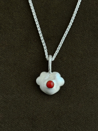 Silver necklace with a five-petal heart-shaped pendant featuring a coral stone on a dark background