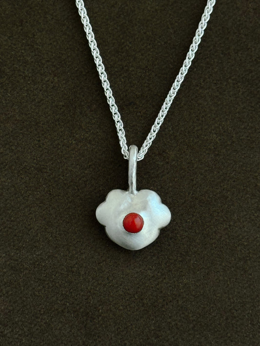 Silver necklace with a five-petal heart-shaped pendant featuring a coral stone on a dark background